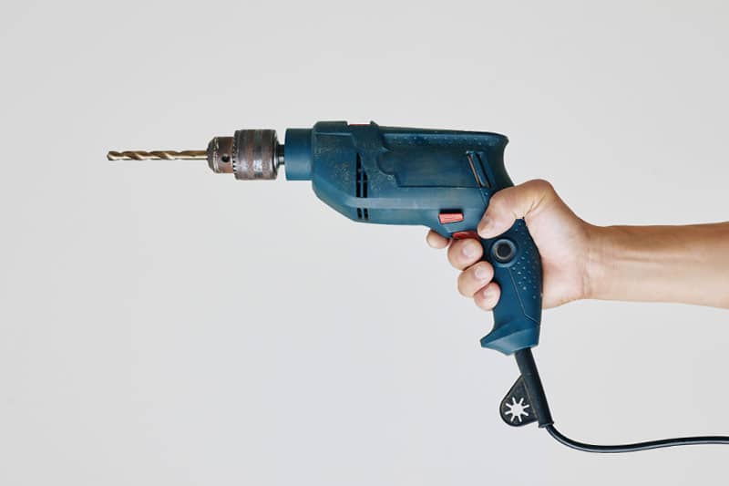 Image of man holding a drill for Urban Garden Sheds blog article on custom fit outs
